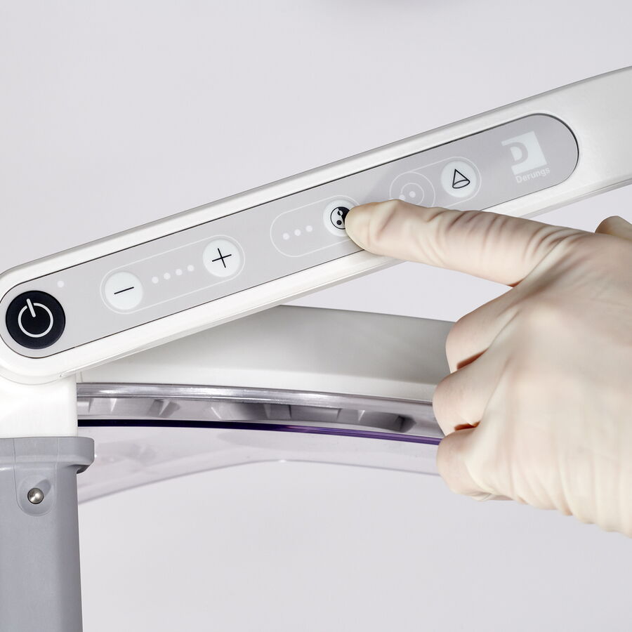 Hand mit Handschuh bedient das Touchpanel einer OP-Leuchte zur Einstellung von Licht und Position